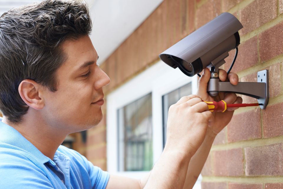 Security Consultant Fitting Security Camera To House Wall