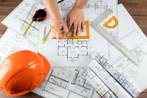 Male hands, Orange helmet, pencil, architectural construction drawings, tape measure. The architect designs the building. The concept of architecture, construction, engineering, design. Copy space.