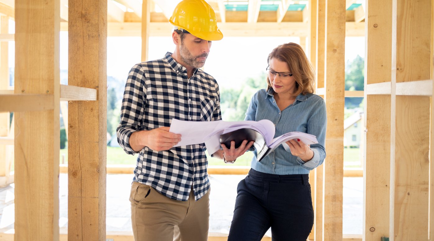 Female homeowner consults blueprints with architect or engineer on construction site of her new house