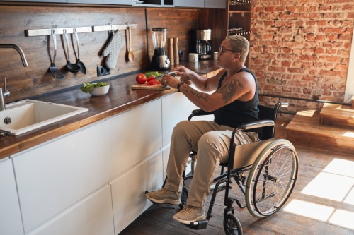 Full length portrait of contemporary tattooed woman with disability cooking dinner at home, copy space