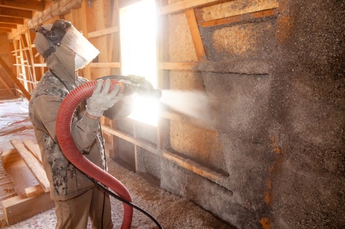 Spraying cellulose insulation on the wall