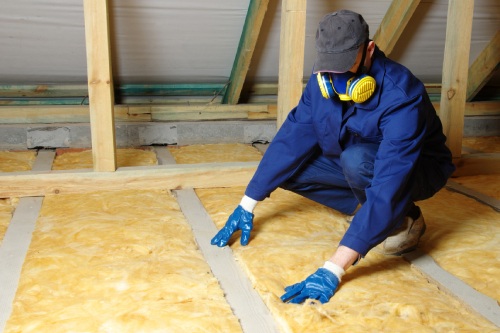 Man installing thermal roof insulation layer using mineral wool.