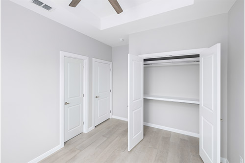 A room with white walls and a ceiling fan, showcasing a clean and modern design for potential tri-plex homes in Texas.