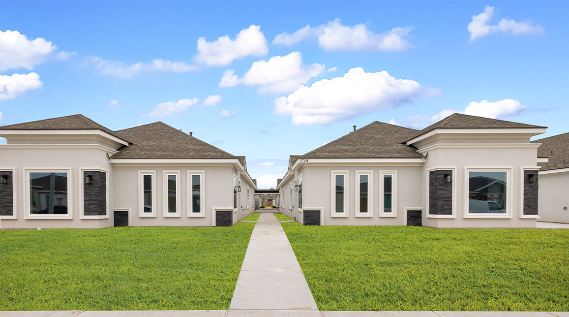 A large white house with a walkway and lawn, representing Tri-Plex, Four-Plex, and Six-Plex homes in Texas.