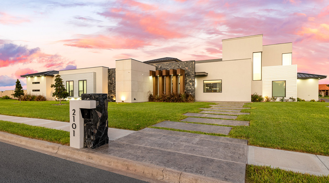 Contemporary house with a driveway and green lawn, highlighting future home design trends for the RGV area in 2026.
