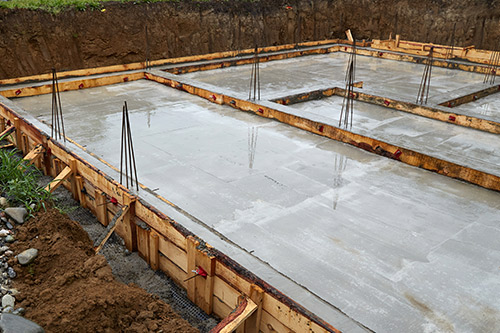  A concrete foundation is being poured in a backyard, preparing for a home build before the hurricane season.