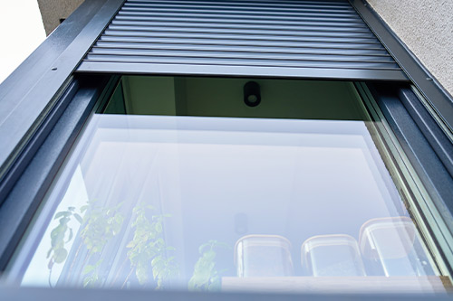 A window featuring a shutter, typical of homes constructed prior to hurricane season for added safety.