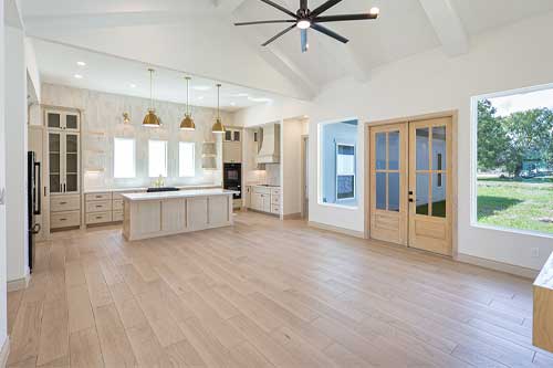An expansive kitchen with wooden flooring and a ceiling fan, designed for comfort and functionality.
