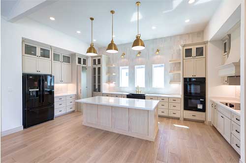 A large kitchen with sleek white cabinetry and rich wooden flooring, offering a modern and cozy cooking space.