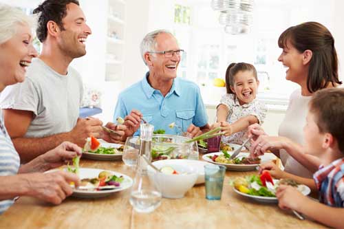Multi Generation Family Eating Meal Around Kitchen Table